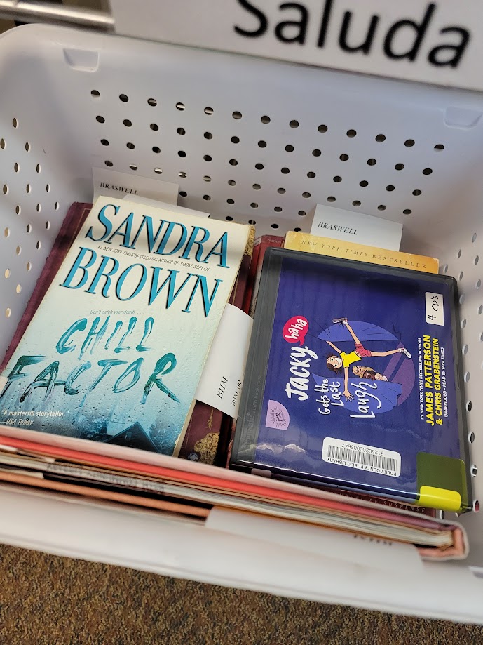 Materials including books and audiobooks stacked neatly in a bin.