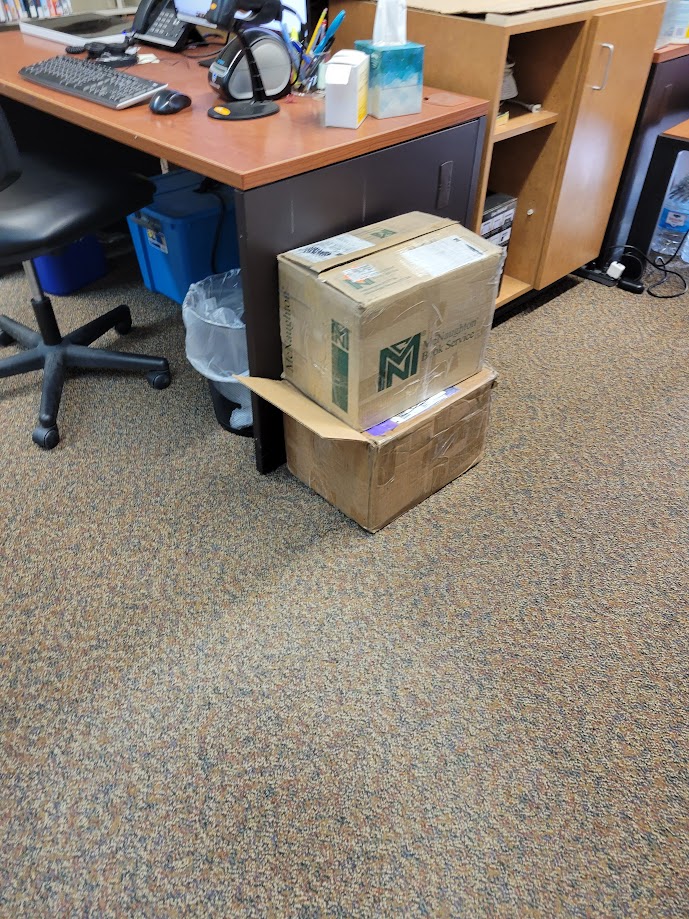 Two damaged boxes have been placed next to a desk for breaking down later.