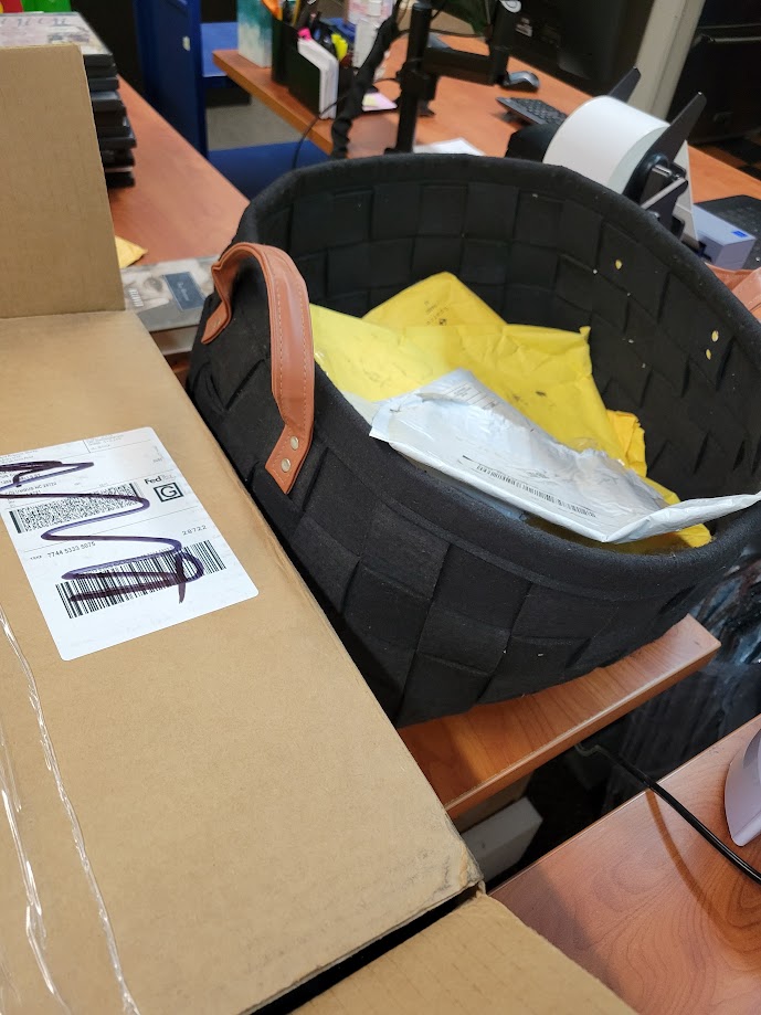 A black basket filled with padded envelopes of varying sizes for packing AV materials.