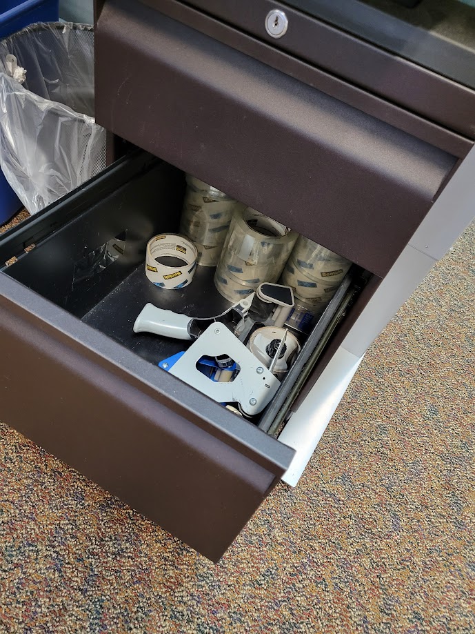 A cabinet drawer containing tape rolls and tape "guns."