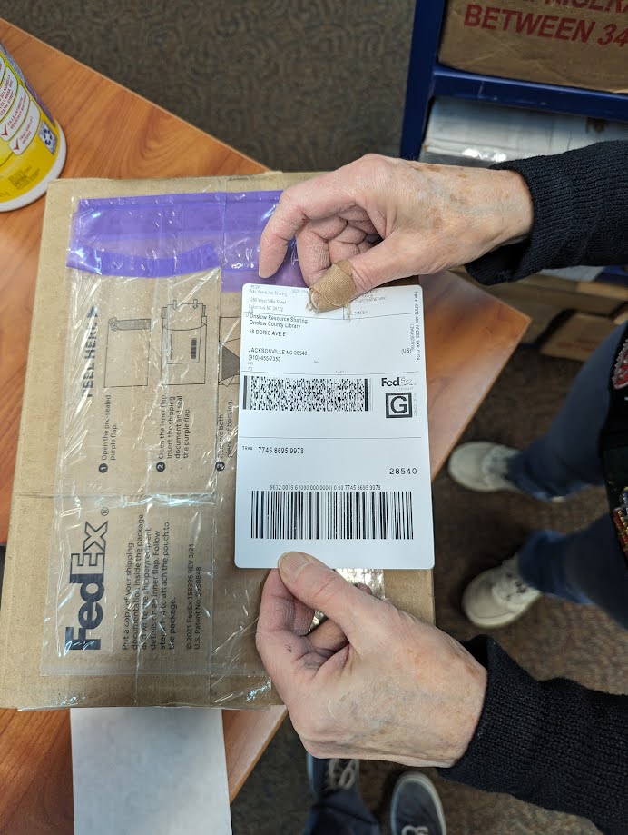 Placing a shipping label parallel to the seam so it is not cut when the box is opened.